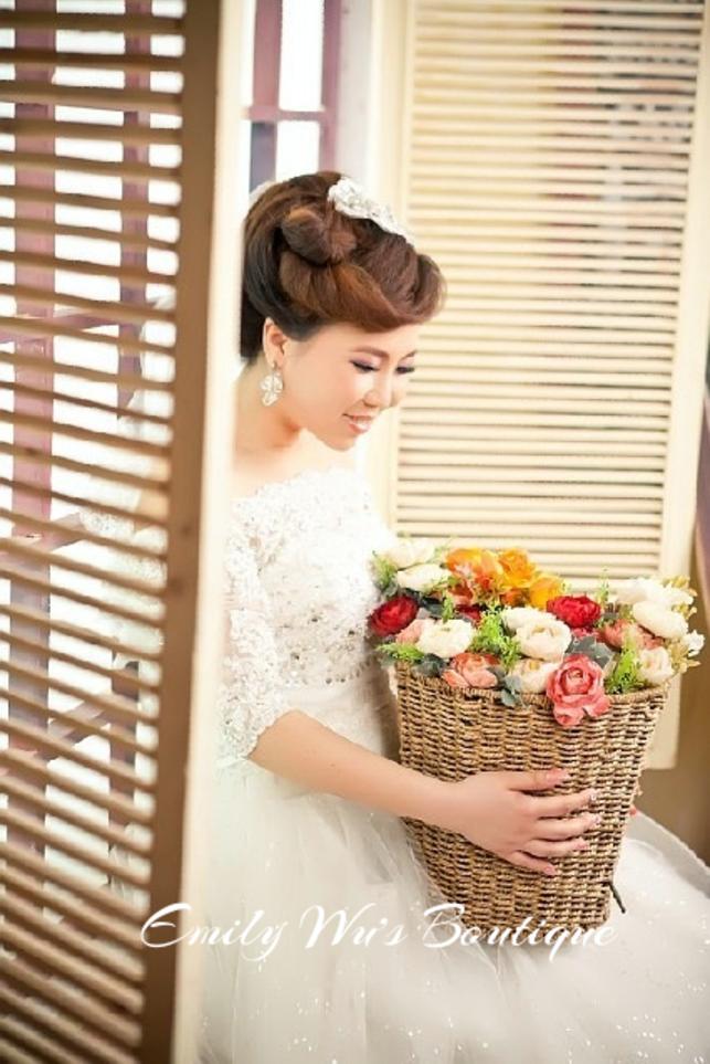Window-lit bridal portrait with a sculpted updo and a colorful bouquet.