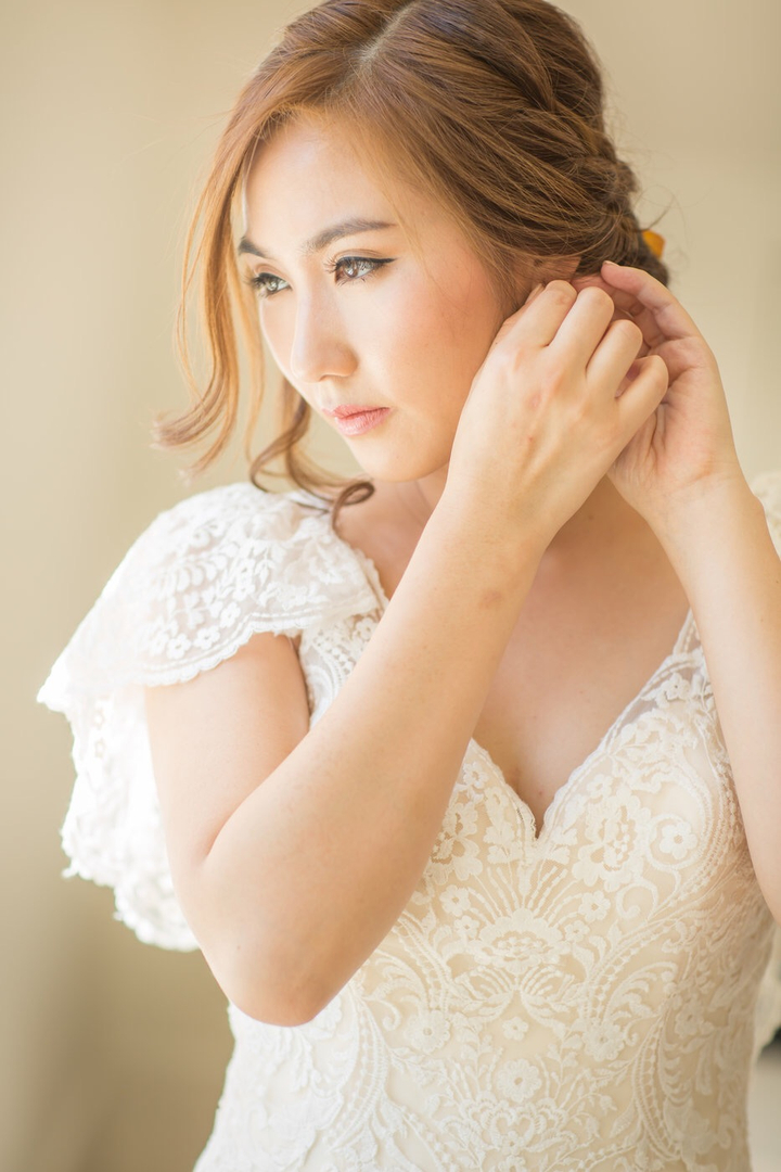 Bridal portrait with a softly swept updo, warm makeup and lace dress.